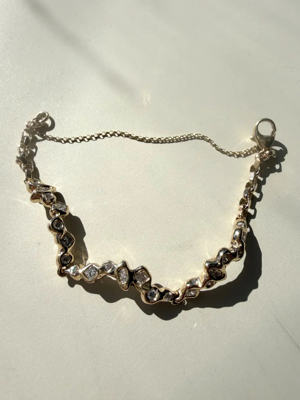 The whole bespoke bracelet laid flat in hard sunlight, showing its clasp and chain