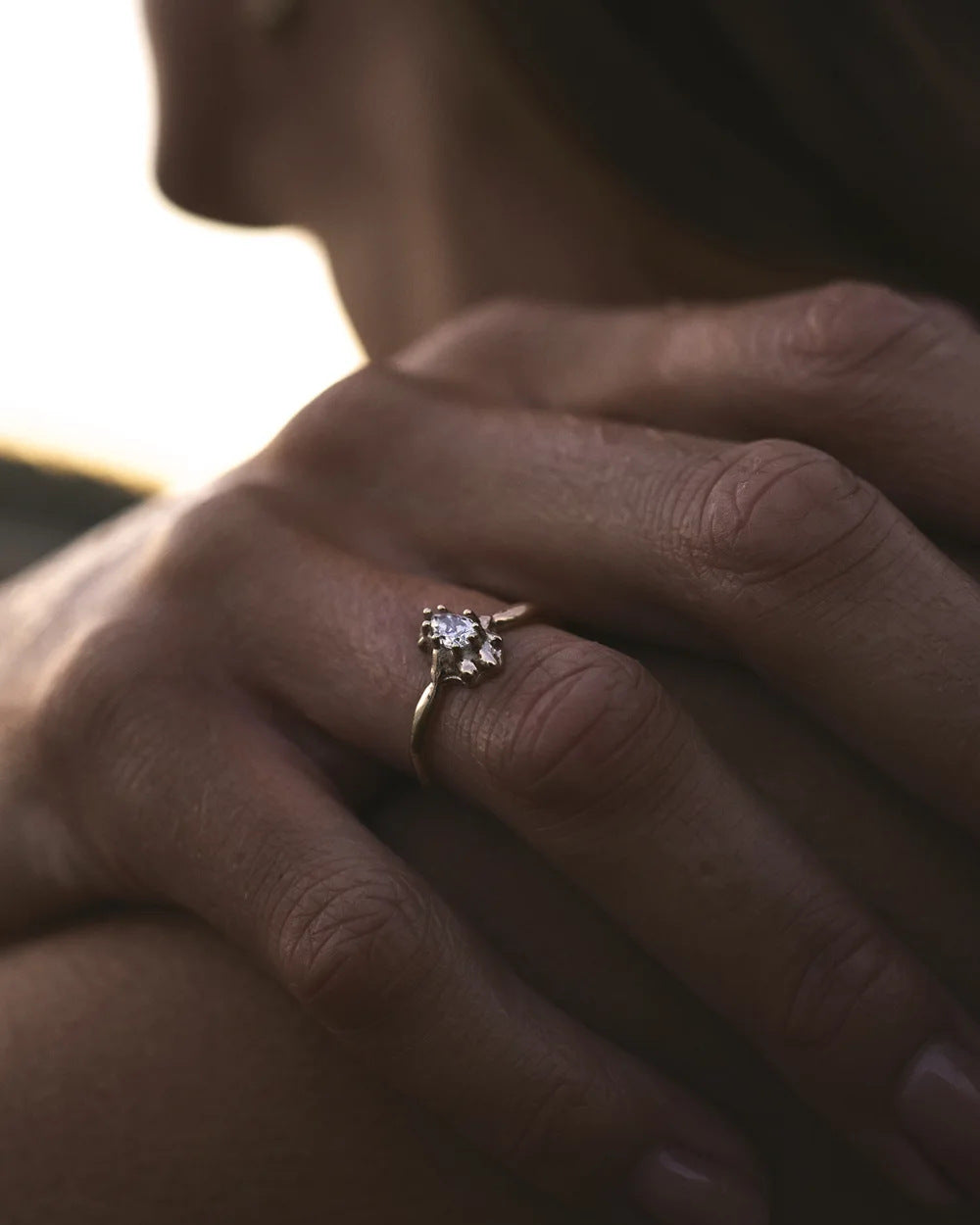 Diamond star ring worn on a hand resting on a shoulder at sunset