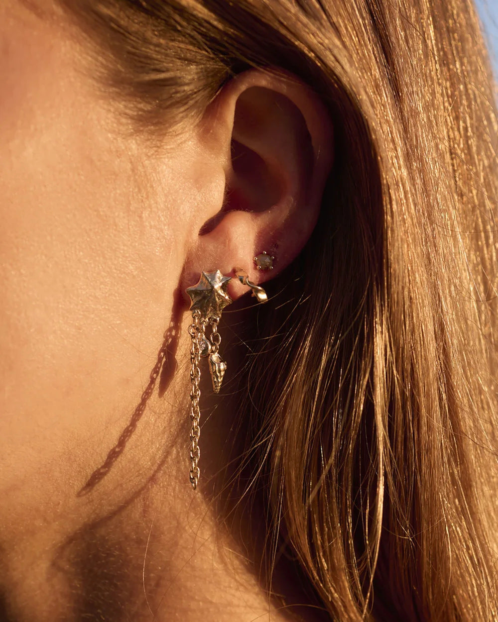 Rippled gold hoops stacked along the ear in low golden light