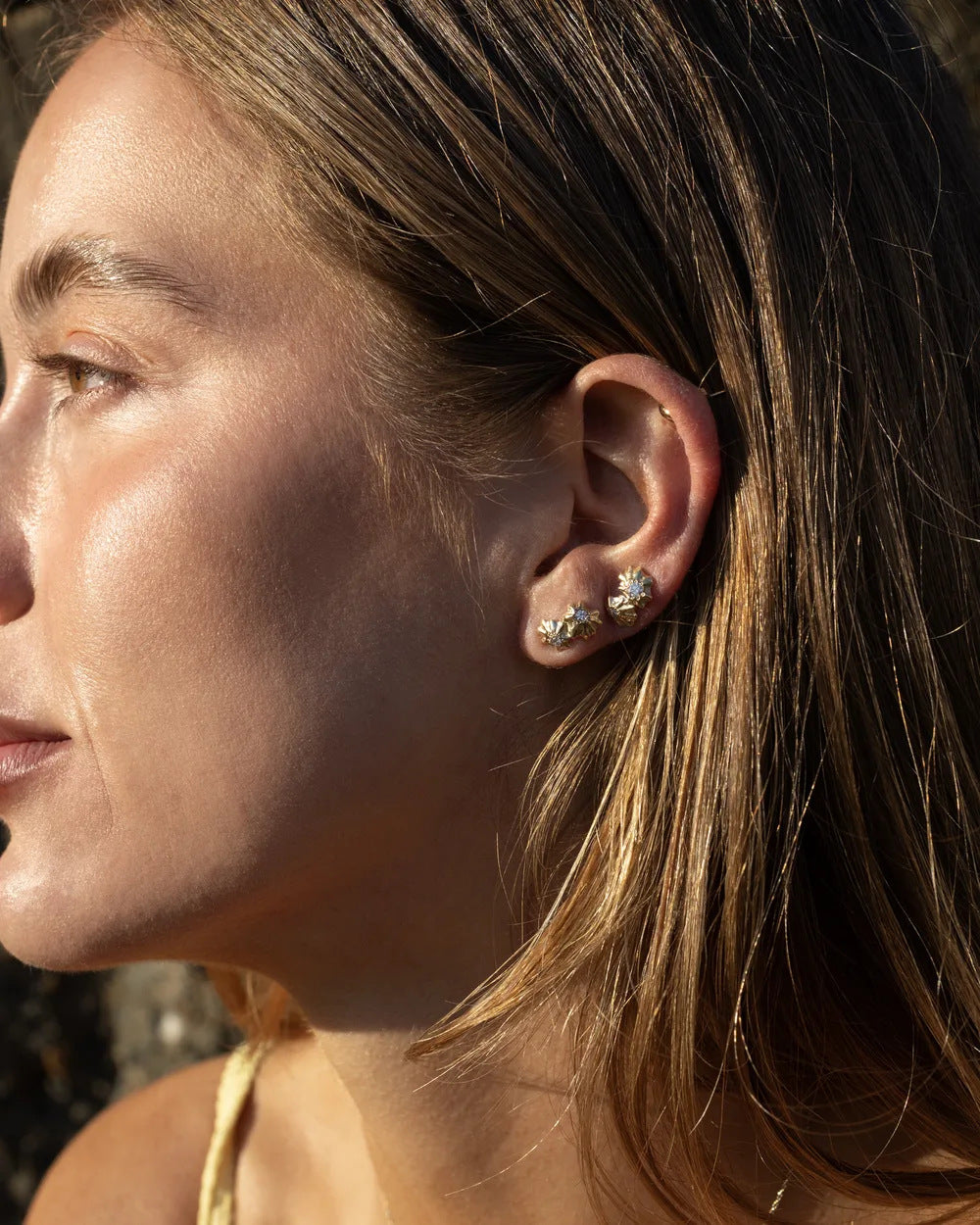 Star Limpet stud earrings worn along the ear in warm evening light