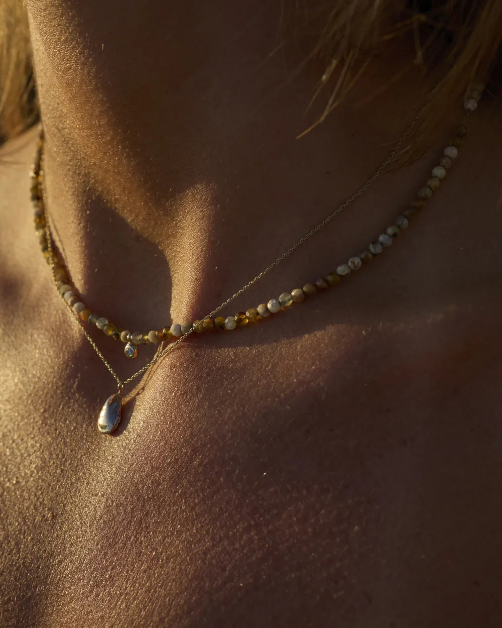 Yellow opal beaded necklace worn at the collarbone in evening light