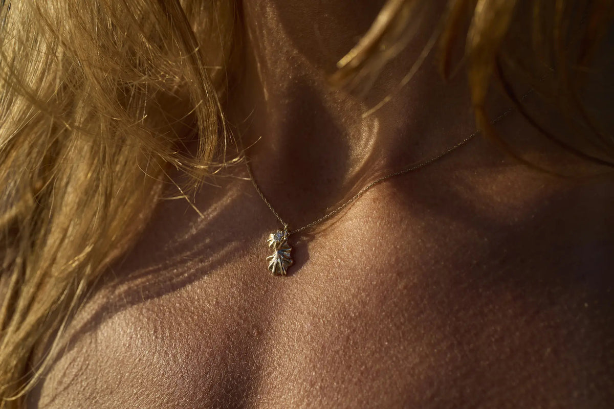 Star Limpet gold shell pendant worn against sun-warmed skin